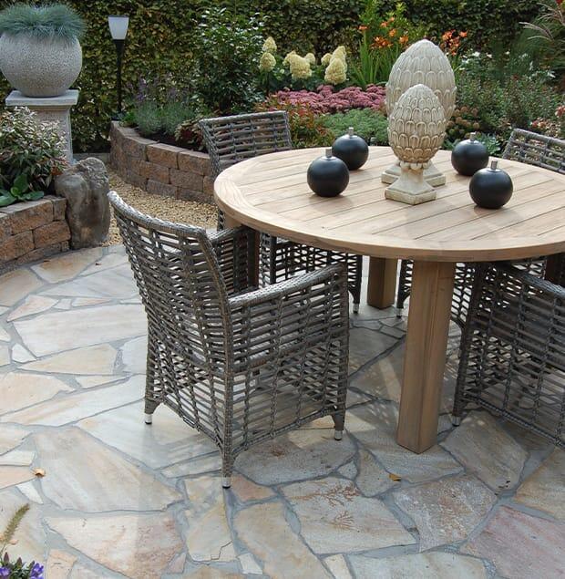 Terras met ronde houten tuintafel en gele flagstones